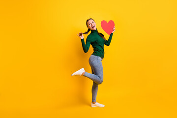 Fototapeta na wymiar Full length body size photo funky girl looking blank space keeping red heart card on date isolated on vivid yellow color background