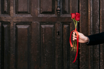 hand giving red roses bouquet to his couple with copy space