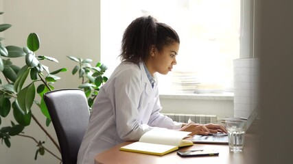 Internship. Enthusiastic young female medical student typing while studying using her laptop indoors. Health, medicine, online education and technology. Side view