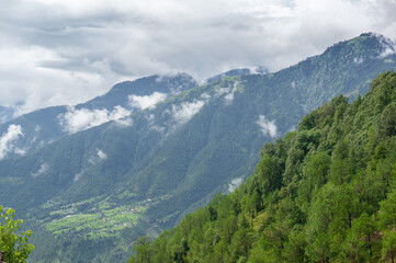Landscape shot of tree covered mountains in the foreground with cloud covered mountain ranges in the distance and deep valleys showing the hill stations of India 