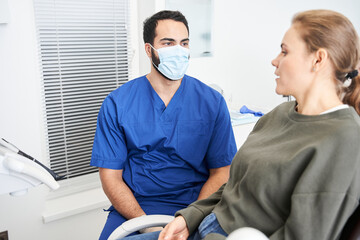 Portrait view of the male dentist in dental office talking with female patient