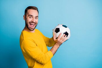 Photo portrait of man with ball smiling laughing in yellow clothes isolated on vibrant blue color background