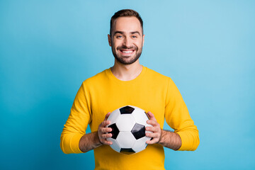 Photo of young handsome happy positive smiling cheerful man hold football ball isolated on blue color background