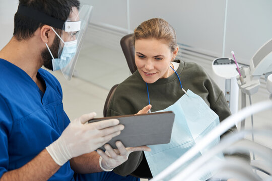 Patient and dentist are looking at teeth image on digital tablet