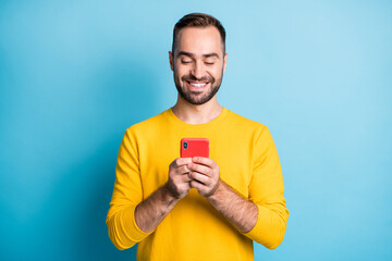 Photo portrait of happy man wearing yellow outfit browsing internet on cellphone smiling isolated...