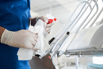 Dentist using antiseptic sanitizer, while cleaning stomatology equipment
