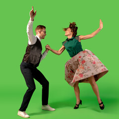 Party. Old-school fashioned young woman dancing isolated on green studio background. Artist fashion, motion and action concept, youth culture, fashion returning. Young stylish man and woman.