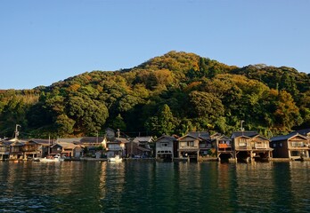 Fototapeta na wymiar View of Funaya, boat houses, with beautiful sun light at Ine bay in Autumn , Ine city, Kyoto, Japan - 京都 伊根の舟屋 秋の景色
