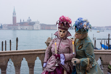Obraz premium Venice, Italy - February 18, 2020: An unidentified woman in a carnival costume in front of a group of gondolas and St Giorgio's Island, attends at the Carnival of Venice.