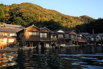 Fototapeta na wymiar View of Funaya, boat houses, with beautiful sun light at Ine bay in Autumn , Ine city, Kyoto, Japan - 京都 伊根の舟屋 秋の景色