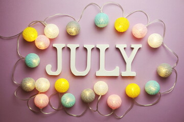 July alphabet letter with cotton ball LED decoration on purple background