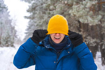Fototapeta na wymiar Smiling happy young man in winter jacket in snowy winter forest, Christmas vacation