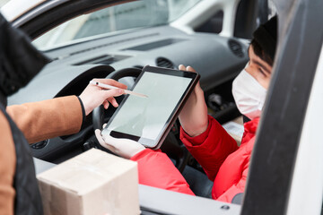 Customer girl sign at the tablet while taking box