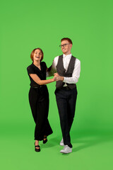 Rock n roll. Old-school fashioned young woman dancing isolated on green studio background. Artist fashion, motion and action concept, youth culture, fashion returning. Young stylish man and woman.