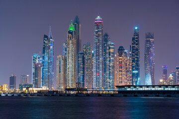 Fototapeta na wymiar Night view to Dubai panorama. Amazing illumination of the modern iconic skyscrapers at twilights. Shot at blue hour.
