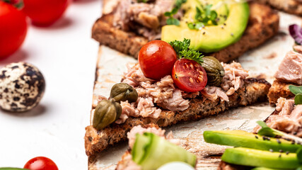 Appetizer bruschetta with tuna. Italian bruschetta sandwiches with canned tuna, tomatoes and capers. toasts with tuna delicious healthy food on a dark background, Top view, flat lay