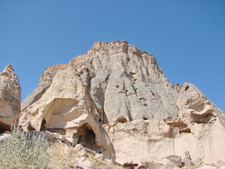 Panorama from the bottom of impregnable rocks on a background of sunny blue sky under the rays of...