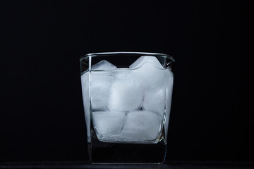 Iced water in a glass on a black background. Pieces of ice. clean drinking water. refreshing water