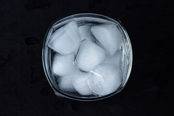 Iced water in a glass on a black background. Pieces of ice. clean drinking water. refreshing water