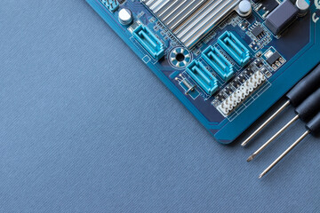 Computer motherboard and three small screwdrivers on a gray paper background with copy space....