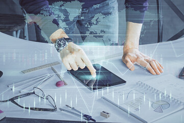Double exposure of man's hands holding and using a digital device and forex graph drawing....
