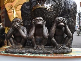 Three monkeys, don't say, don't hear, don't see, in fron of a gorilla and a buddha