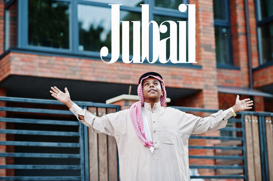 Jubail - biggest city of Saudi Arabia. Middle Eastern saudi arabian man posed on street against modern building up his hands in the air.
