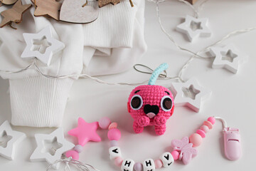 Pink knitted cherry toy with eyes lies on the table. Translate: Anna