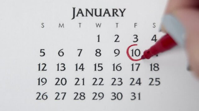Female hand circle day in calendar date with a red marker. Business Basics Wall Calendar Planner and Organizer. JANUARY 10th