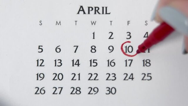 Female hand circle day in calendar date with a red marker. Business Basics Wall Calendar Planner and Organizer. APRIL 10th