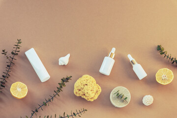 Cosmetic oil, serum and organic soap. Eco-friendly spa, massage, peeling and hydration products. Beige background, lemon fruits and eucalyptus leaves. Top view, flat lay, copy space.