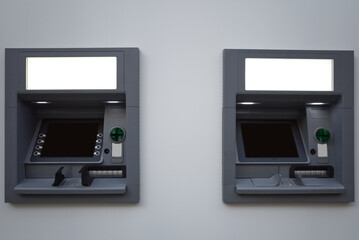 Front view of 2 ATM, automated teller machine, machine on white wall.