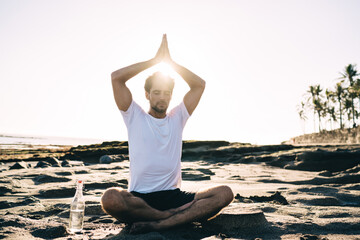 Concentrated man doing Lotus pose with Namaskar Mudra gesture under head