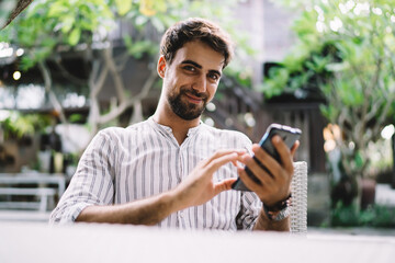 Glad guy using social media on smartphone in cafe