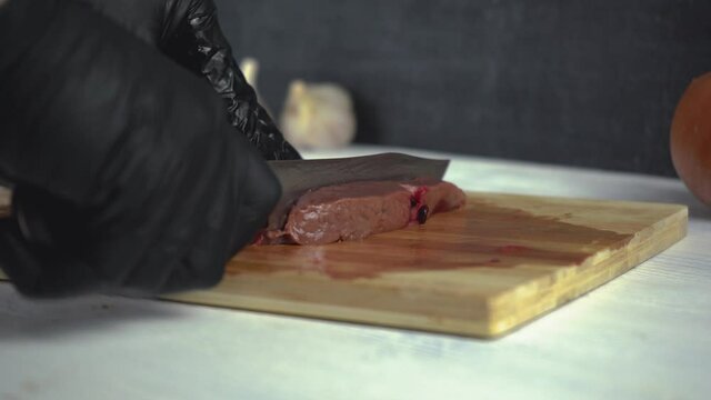 Chef carves beef liver on a wooden cutting board