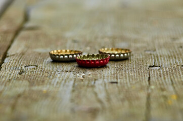 Three bottle caps on wooden plank