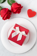 Plate with tableware, ribbon, gift and roses for Valentine's Day special meal concept.