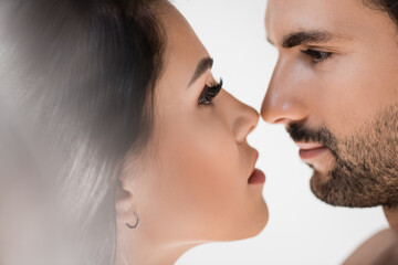 Bearded man looking at brunette girlfriend on blurred foreground isolated on white