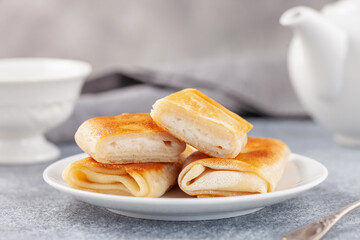 Pancakes envelopes with cottage cheese, curd or ricotta in a plate on a grey background
