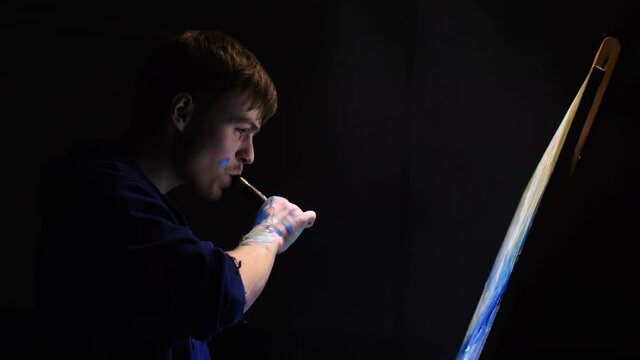 Artist copyist paint seascape with ship in ocean. Vaper smoke vape e-cigarette. Craftsman decorator draw as boat sail on blue sea with acrylic oil color. Draw finger, brush, knife palette. Indoor.