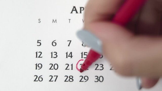Female hand circle day in calendar date with a red marker. Business Basics Wall Calendar Planner and Organizer. APRIL 22th