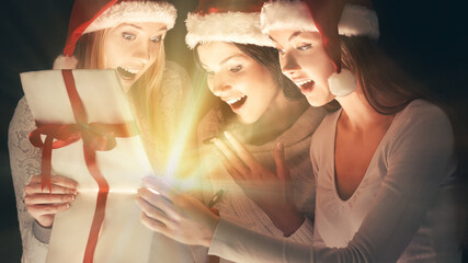 group of female students in costumes of Santa Claus opening a box of Christmas gifts .