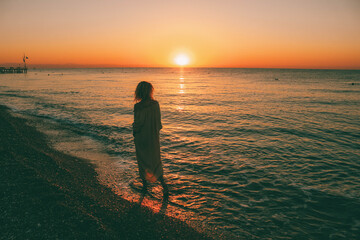 Fototapeta premium A girl walking on the beach at sunrise