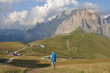 Kobieta schodzi łąką z górskim łańcuchem w tle, Dolomity, Włochy © Marta