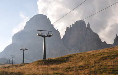 Przęsła kolejki górskiej na tle poszarpanej grani Sassolungo, Dolomity, Włochy