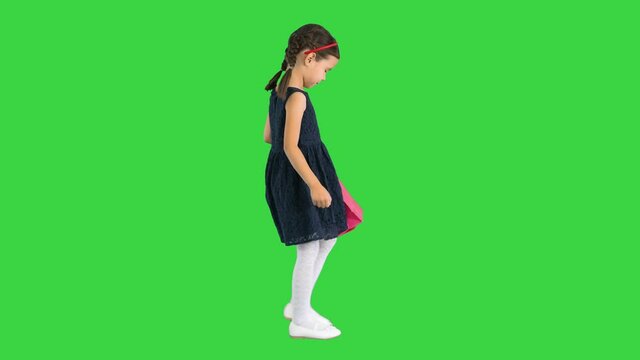Beautiful little girl in black dress walking with shopping bags on a Green Screen, Chroma Key.