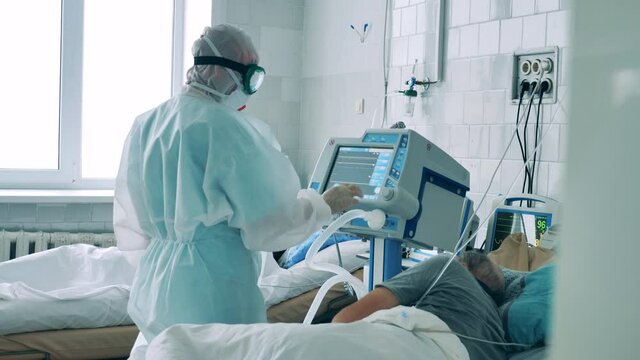 Doctor in a hazmat suit is operating a medical monitor. Coronavirus, covid-19 pandemic concept. - Powered by Adobe