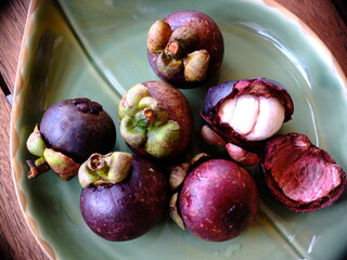 Obraz premium Mangosteen (Garcinia mangostana) on a green platter