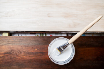 Flat lay. A container with paint and a brush. The horizontal boards are painted with white paint and a brush. Renovation and design. Place for your text. Copy space.