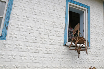 A man throws an old chair out of the window